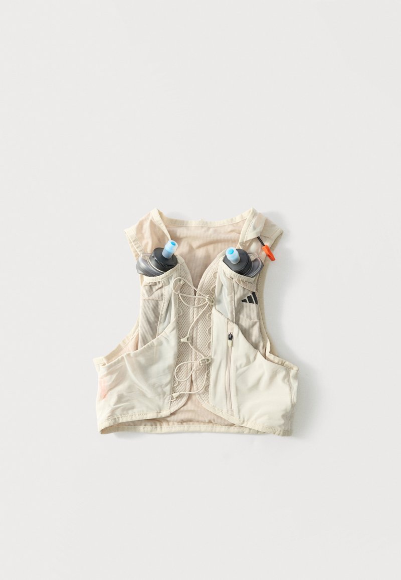 Šviesiai smėlio spalvos hidracijos liemenė su dviem priekinėmis vandens buteliukų kišenėmis ir užtrauktuku užsegama kišene, skirta bėgimui ar lauko veikloms.