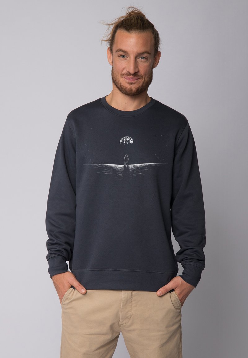 Donkergrijze sweatshirt met lange mouwen, ronde halslijn en een grafische afdruk van een figuur met een boom op de horizon. Zachte textuur.