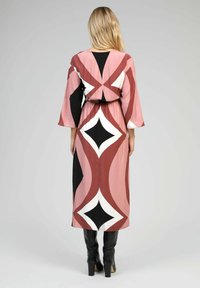 Robe maxi rose, noire et blanche avec des motifs géométriques. Présente une coupe décontractée, de longues manches évasées et un détail de taille élastique.
