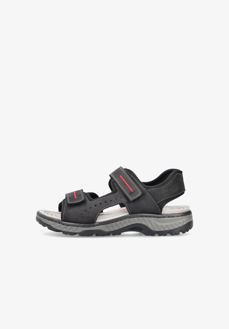 Sandales en cuir noir avec des sangles Velcro ajustables, design perforé, semelle en caoutchouc grise et touches rouges le long des sangles.