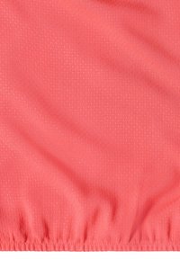 Tissu de couleur corail avec de petites perforations et un bord élastique froncé en bas, montrant la texture et de légers plis.