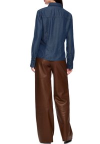 Denim jacket with a collar, long sleeves, and buttoned cuffs, paired with brown leather wide-leg trousers. Smooth texture and fitted design.