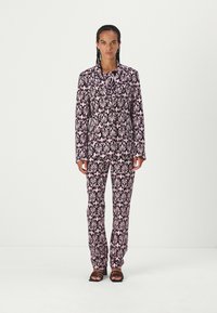 Pink floral patterned suit with a tailored jacket and matching pants. Made of lightweight fabric, featuring a slim fit and a smooth texture.
