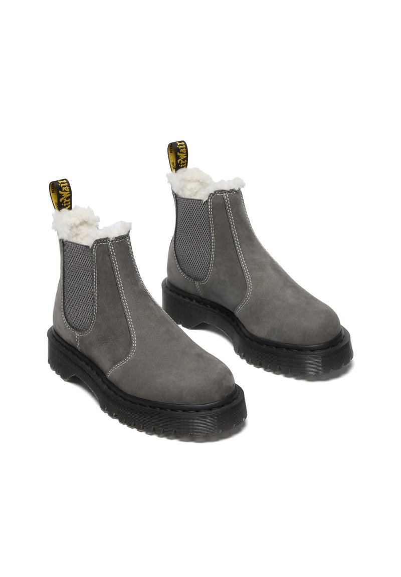 Grijze suede enkellaarzen met een sheepskin voering, elastische mesh zijpanelen en een zwarte rubberen zool. Voorzien van een gele trekband aan de achterkant.