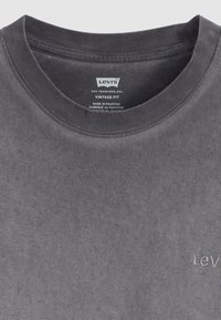 Szürke pamut póló kerek nyakkivágással és egyszínű textúrával. Egy kis hímzett logó található a mellkason, amely "Levi's Vintage Fit" felirattal van ellátva.