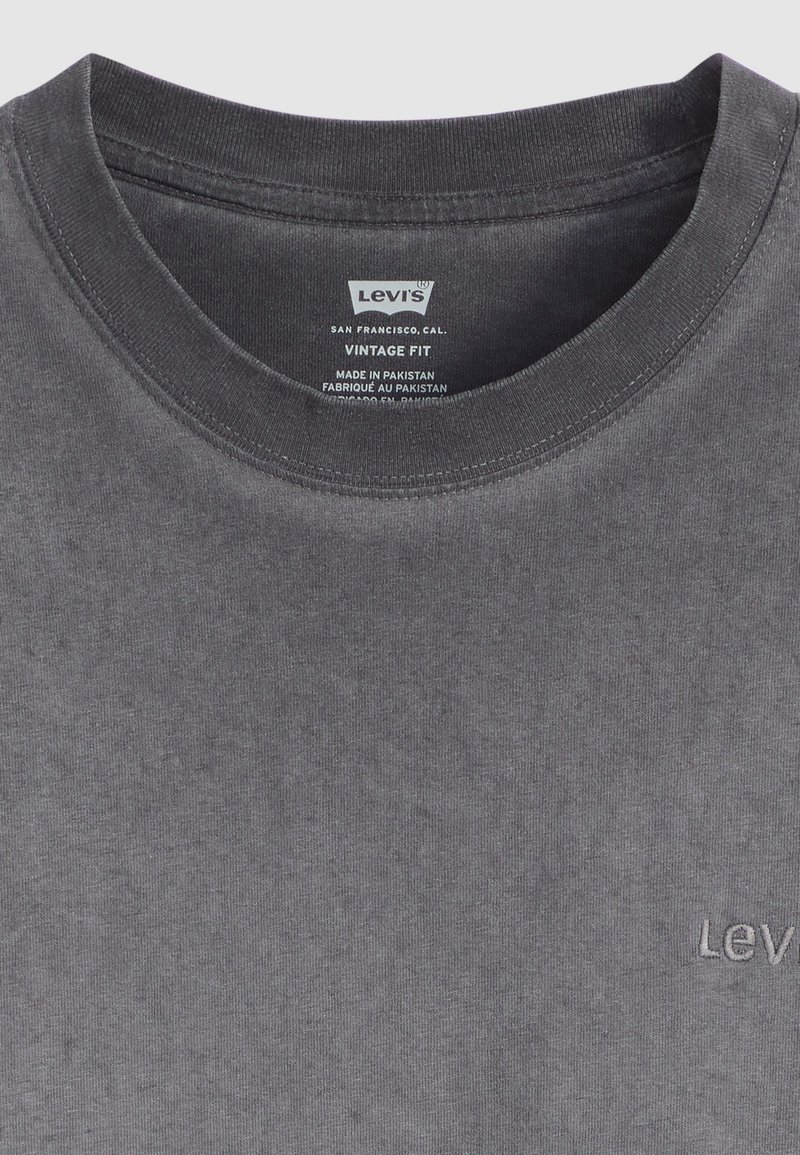 T-shirt en coton gris avec un col rond et une texture unie. Présente un petit logo brodé sur la poitrine, étiqueté "Levi's Vintage Fit."