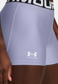 Under Armour kratke hlače u svijetloj lavandi, napravljene od glatkog, rastezljivog materijala; sadrži crni elastični pojas s bijelim logotipom.
