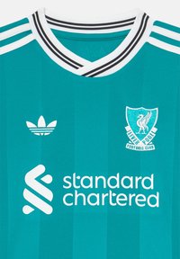 Mėlynas futbolo marškinėliai su baltu Adidas logotipu, Liverpulio FC emblemą, „standard chartered“ rėmėjo tekstu, juodai baltu dryžuotu V formos apykakle.