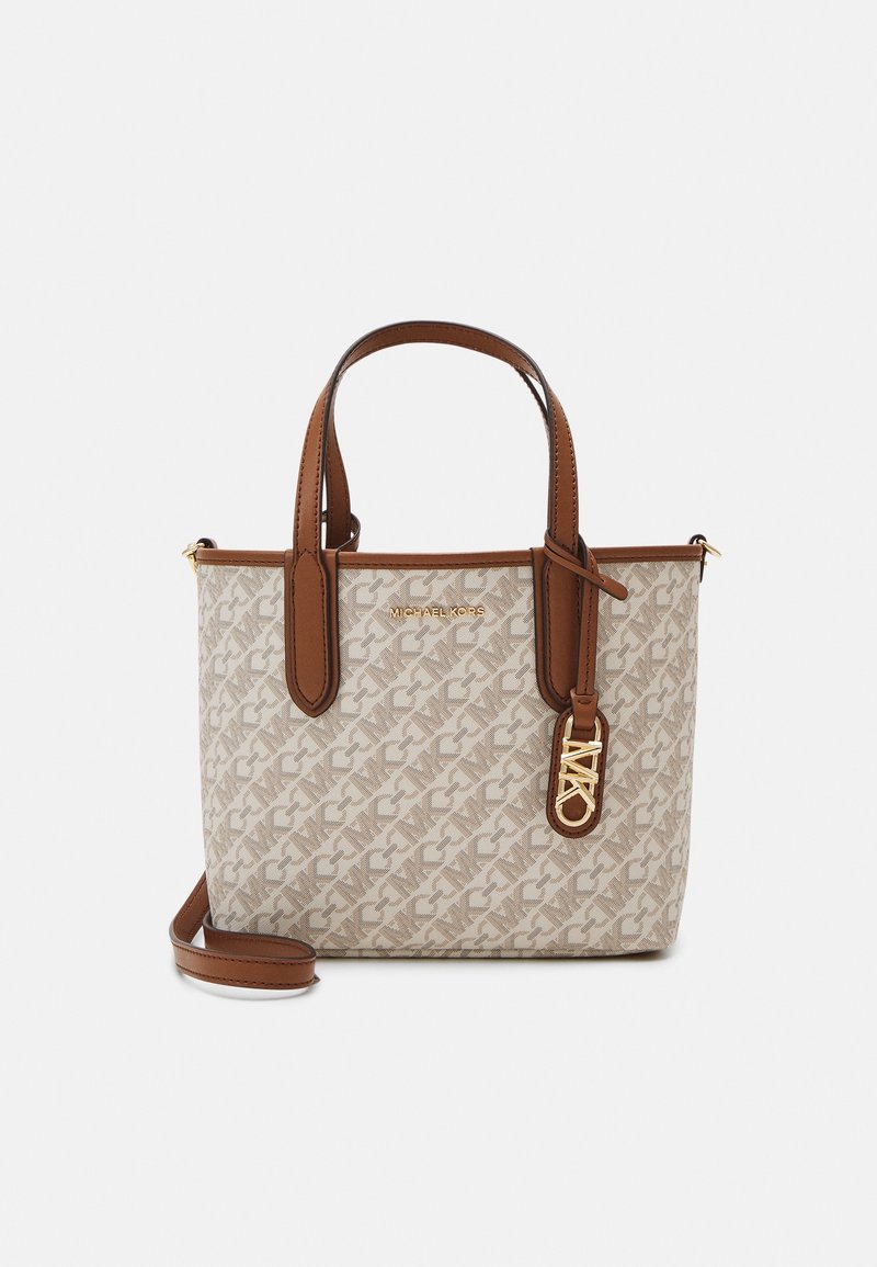 Michael Kors beige olkanen laukku, jossa on logoprintti ympäriinsä, ruskeat nahkahihnat ja irrotettava olkahihna valkoista taustaa vasten.