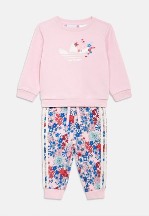 Pink children's sweatshirt with white Adidas logo and floral embroidery, paired with matching pink floral print pants with white side stripes.