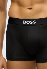 Fekete boxeralsó puha, fehér "BOSS" felirattal díszített elasztikus derékrésszel. Sima anyagból készült, testhezálló szabással.