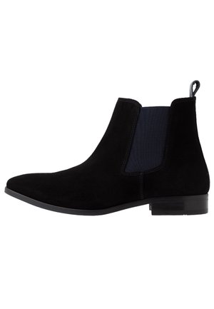 Bottine Chelsea en daim noir avec panneau latéral élastique, petit talon, bout arrondi et languette à l'arrière.