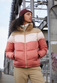 Columbia puffjacka med tri-färgad design: beige, ljusrosa och korall. Vadderad textur med hög krage och dragkedja.