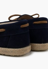 Marineblaue Wildlederschlupfschuhe mit gewebten Jutesohlen und braunen Lederakzent-Schnürsenkeln, ausgestattet mit einem weichen Innenfutter für zusätzlichen Komfort.