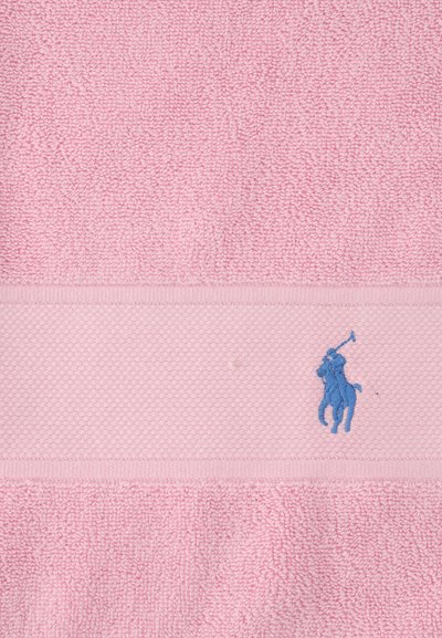 Ροζ πετσέτα με υφή σε μπάντα και μπλε κεντημένο λογότυπο παίκτη πόλο πάνω σε άλογο που κρατά ένα μαλέτι.