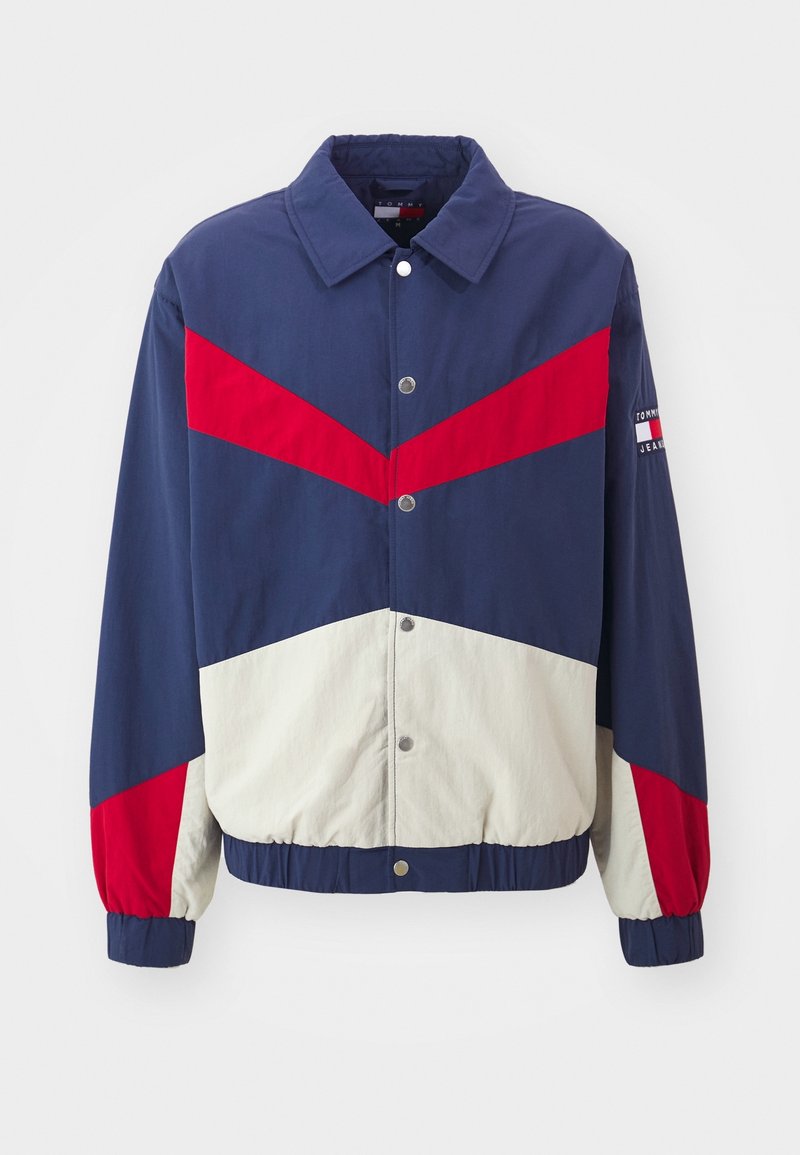 Veste à blocs de couleur bleu marine, rouge et blanc avec boutons-pression, poignets et ourlet élastiques, et logo Tommy Jeans sur la manche gauche.
