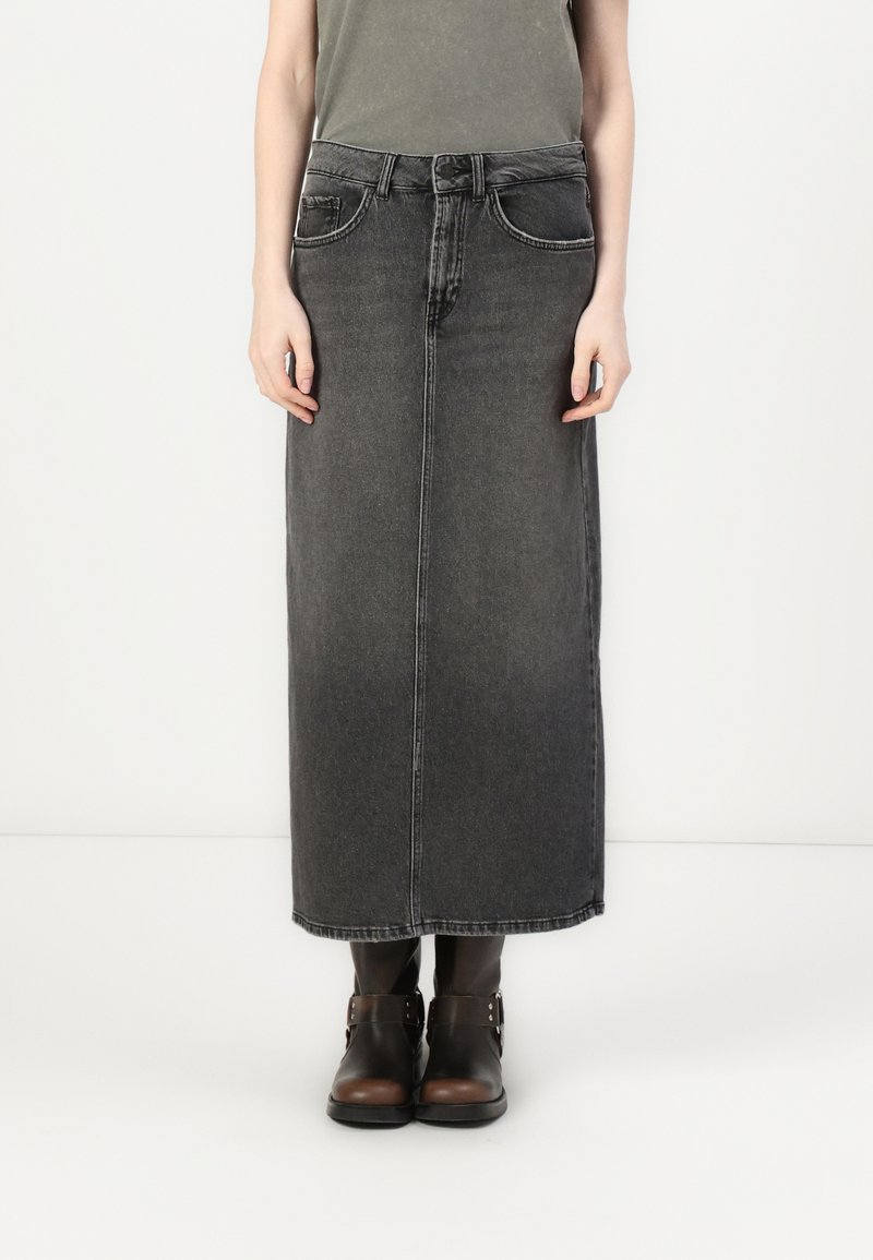 Black denim maxi skirt with a straight cut, front pockets, and belt loops. Paired with brown ankle boots. Smooth texture and subtle fading.