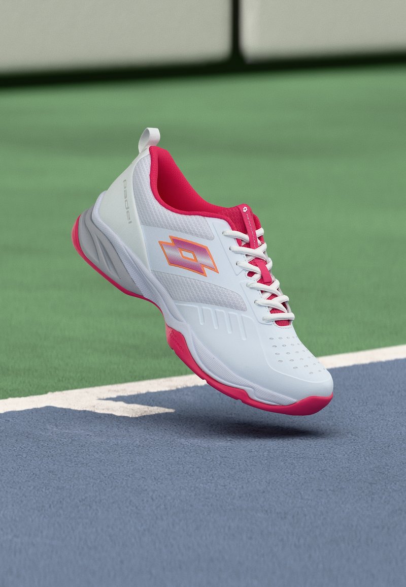 Λευκό και ροζ αθλητικό παπούτσι με πορτοκαλί λογότυπο που αιωρείται πάνω από γήπεδο τένις μπλε και πράσινου χρώματος κοντά στη γραμμή ορίου.