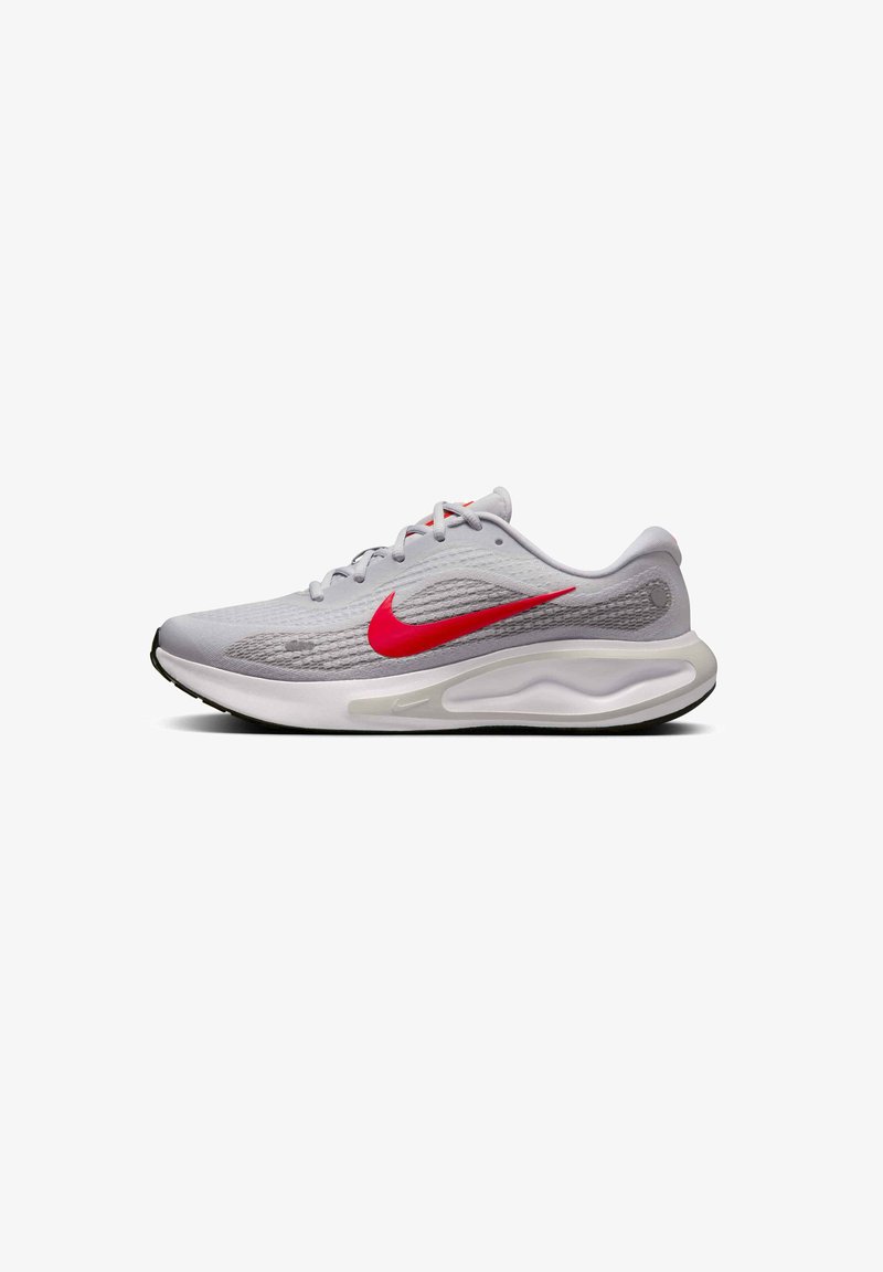 Jasnoszary but sportowy z siateczkową cholewką, czerwonym logo Nike oraz wyścieloną białą podeszwą. Posiada okrągły obcas i subtelne fakturowane detale.