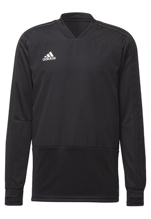 Homme portant un haut de sport à manches longues noir Adidas et un pantalon assorti avec des logos blancs Adidas sur la poitrine et la cuisse.