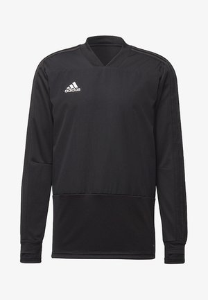 Homme portant un haut de sport à manches longues noir Adidas et un pantalon assorti avec des logos blancs Adidas sur la poitrine et la cuisse.