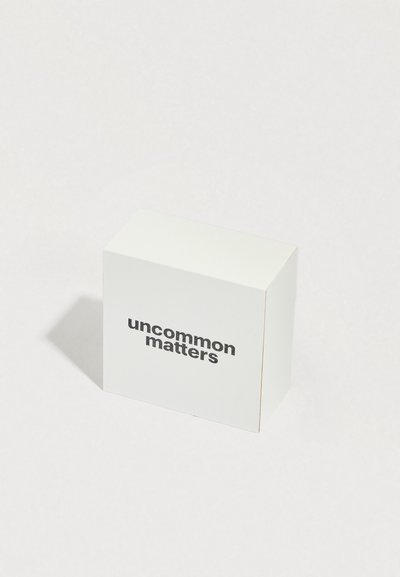 Valkoinen pahvilaatikko, jonka reunat ovat hieman pyöristetyt, ja etupuolella on teksti "uncommon matters" lihavoidulla mustalla fontilla.