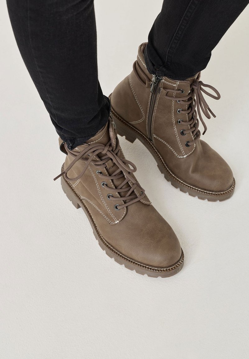 Brown leather ankle boots with a rounded toe, lace-up front, side zipper, and textured rubber sole. Contrast stitching accents the design.