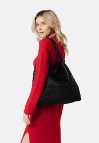 Czarna pleciona torba tote o miękkiej, teksturowanej powierzchni. Posiada dwa mocne uchwyty oraz przestronny design, idealna do codziennego użytku.