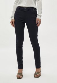 Pantaloni tailored blu navy con vestibilità slim, dotati di chiusura a bottoni e passanti per cintura, realizzati in un tessuto morbido e elasticizzato.