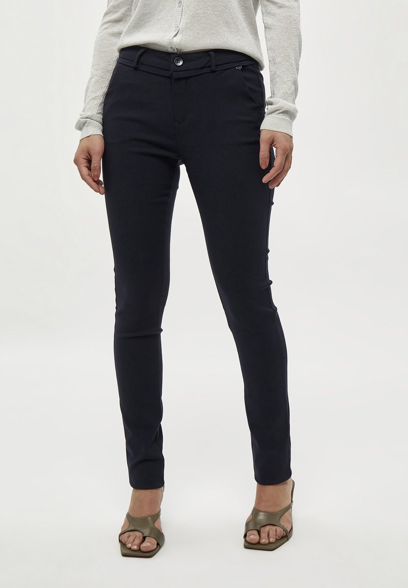 Pantaloni tailored blu navy con vestibilità slim, dotati di chiusura a bottoni e passanti per cintura, realizzati in un tessuto morbido e elasticizzato.