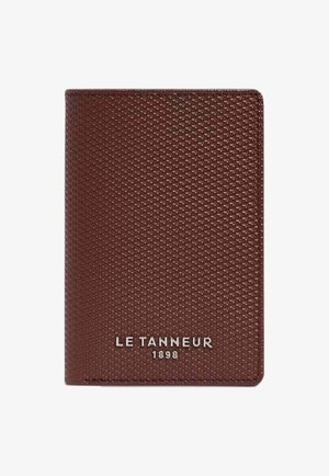 Braune Lederbrieftasche mit strukturierter Oberfläche, die ein silbernes Logo "LE TANNEUR 1898" unten zeigt. Kompakte rechteckige Form.