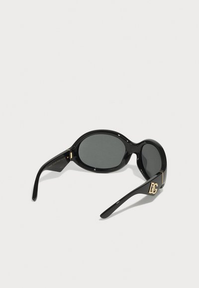 Occhiali da sole ovali neri con lenti scure. Montatura in plastica lucida, con dettagli in tono oro sui rostri. Texture liscia.