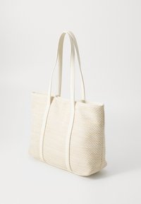 Stor beige vævet tote taske med cremede imiteret læderhåndtag, der har et fiskebensmønster, rummelig indvendig og struktureret form.