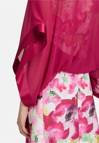 Transparenter Fuchsia-Kimono mit Satinbesätzen, der über einen floral bedruckten Rock mit pinken und grünen Aquarellen fällt und einen geschichteten Look kreiert.