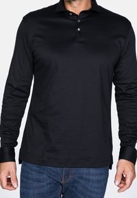 Svart långärmad polo skjorta i mjukt tyg; har en knappad krage, slim fit och sidostickningar för rörelsefrihet.