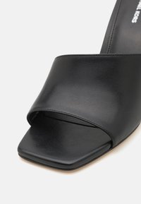 Sorte lædersandal med bred overdel, firkantet tå og glat tekstur. Minimalistisk design uden synlige metaldele.