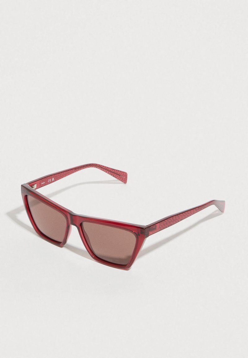 Piros átlátszó napszemüveg barna tónusú, színezett lencsékkel. Szögletes keret kialakítás, mintás díszítéssel a szárakon. Könnyű műanyag anyagból készült.