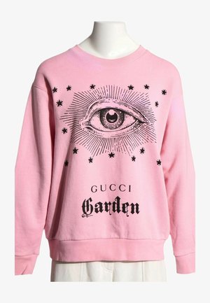 Pinkes Sweatshirt mit großem schwarzem Augengrafik, umgeben von Sternen und dem Text „"GUCCI Garden"“ auf der Vorderseite.