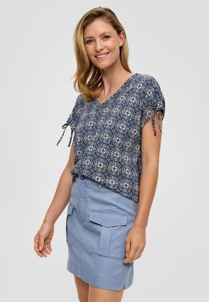 Marineblauwe blouse met een V-hals en strikmouwen, gecombineerd met een lichtblauwe utiliteitsrok met voordozen en een rechte snit.