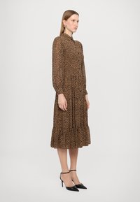 Abito midi con stampa leopardata, colletto alto, chiusura con bottoni, maniche lunghe, orlo arricciato a strati e tessuto leggero e testurizzato.