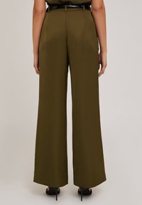 Pantaloni largi de culoare verde măsliniu, cu o textură netedă, talie înaltă și detalii cu curea neagră, având o tăietură evazată la tiv.