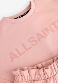 Šviesiai rožinė sportinė maikutė su pintu apykaklės kraštu ir toniniu "ALLSAINTS" logotipu. Savybės: minkšta tekstūra ir susiraukšlėjusi medžiaga apatinėje dalyje.