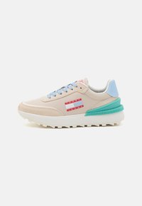 Zapatilla beige con una parte superior de tela texturizada, acentos en azul claro, franjas de logo rojas y una suela verde estriada, con puntera redonda y diseño de cordones.