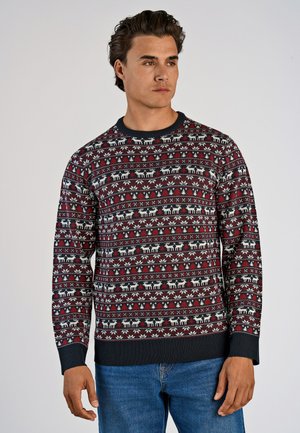 Pull rouge et marine à motif avec des motifs de rennes blancs et des designs floraux. Tissu tricoté avec des poignets et une taille côtelés. Coupe décontractée.