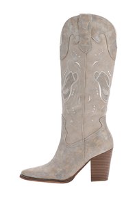 Stivale da cowboy in suede beige con punta affusolata, ricami decorativi e tacco impilato. Caratteristiche includono una linguetta e dettagli di superficie testurizzati.
