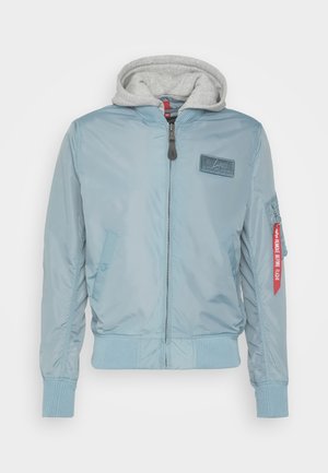 Hele sinine bomber-jakk halli kapuutsiga. Omab ribakäe ja -vööde, esistundi lukuga, nurga all taskut ja punase sildi detailsust.