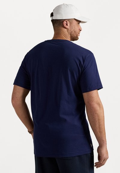 Tricou din bumbac de culoare albastru marin, cu mâneci scurte. Are un guler rotund și un mic detaliu cu logo în partea de jos. Textură netedă.