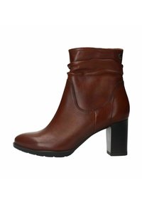 Bottine en cuir brun avec un design flou, embout rond et un large talon noir. Tige texturée avec des coutures discrètes.