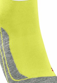 Calcetín deportivo amarillo neón con un talón y punta gris texturizados. Presenta un diseño acanalado y costuras amarillas contrastantes a lo largo de los bordes.