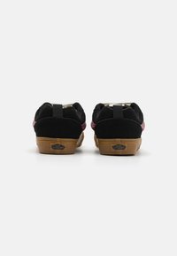 Baskets en suède noir avec un accent bordeaux, dotées d'une semelle en gomme. Comprend une languette à l'arrière et le logo "Vans Off The Wall" sur le talon.